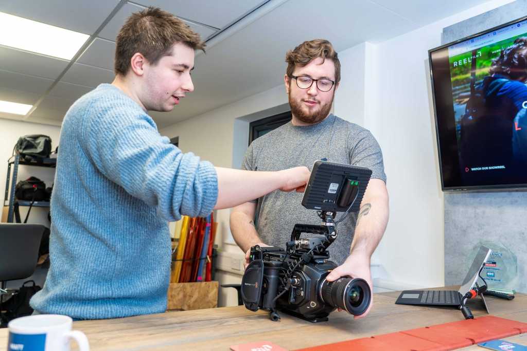 Behind the scenes of the Reel Film team looking at something on the camera