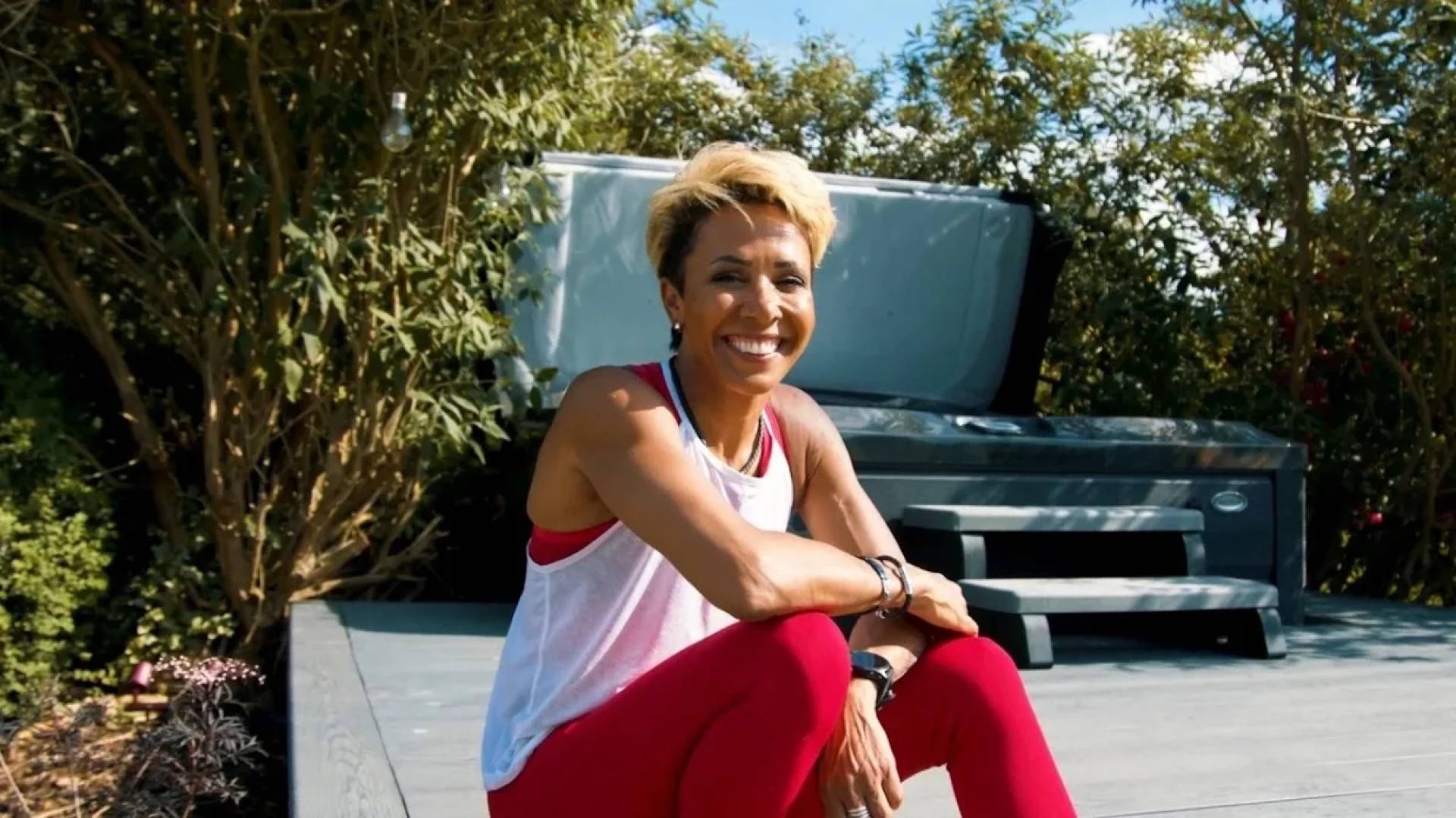 Dame Kelly Holmes smiling in a garden for Jacuzzi podcast content