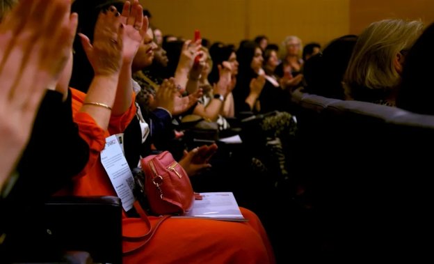 Rows of people applauding in a room